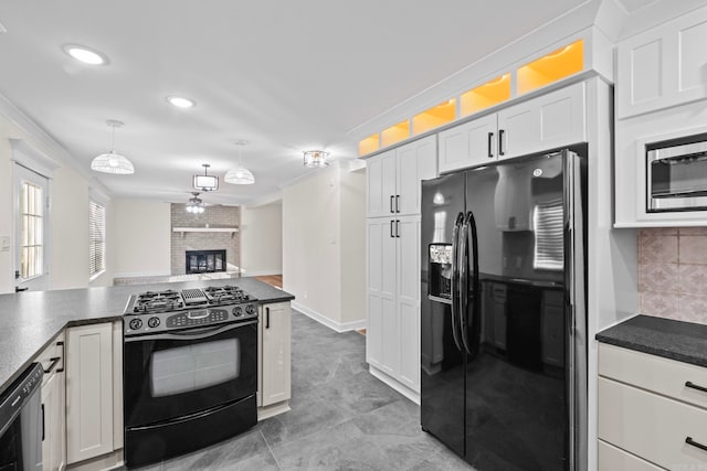 kitchen featuring white cabinets, black appliances, a fireplace, tasteful backsplash, and hanging light fixtures