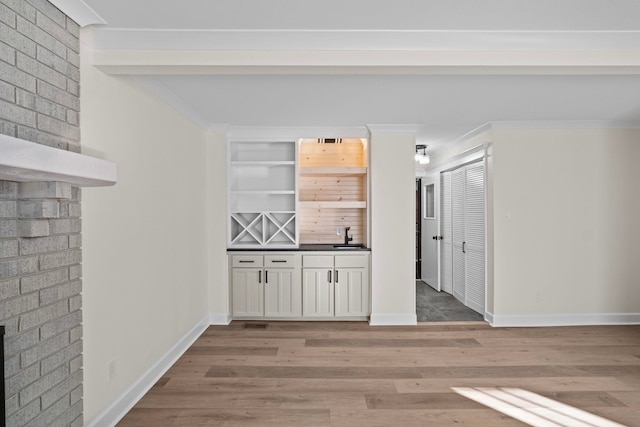 bar featuring white cabinets, hardwood / wood-style floors, a fireplace, and sink