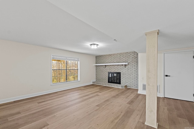 unfurnished living room featuring a brick fireplace and light hardwood / wood-style flooring