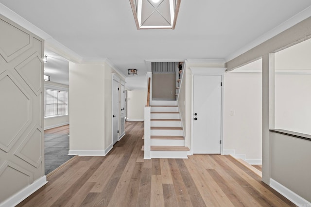 hall with ornamental molding and light hardwood / wood-style floors