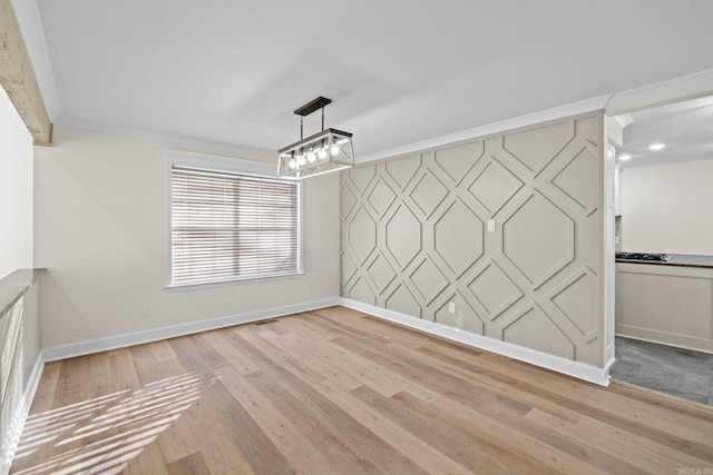 unfurnished dining area featuring crown molding and light wood-type flooring