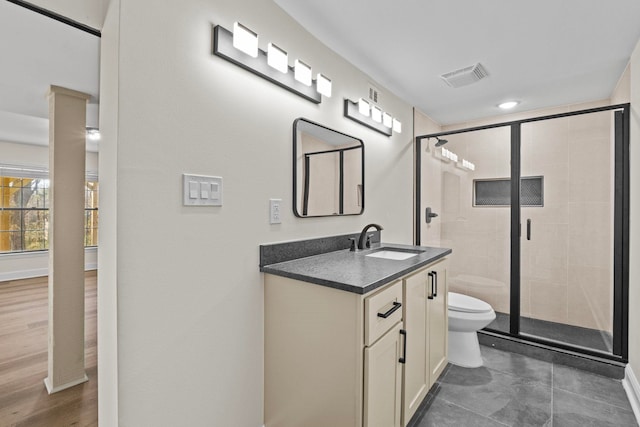 bathroom with a shower with shower door, toilet, and vanity