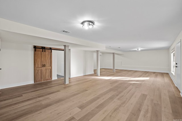 basement featuring a barn door and light hardwood / wood-style floors