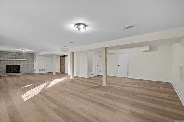 basement with a brick fireplace and light hardwood / wood-style flooring