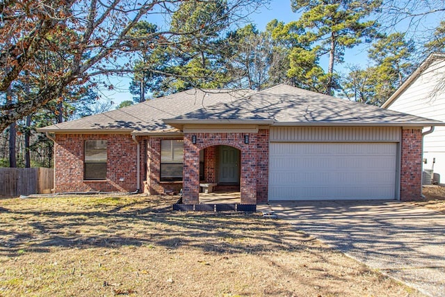 ranch-style house featuring a garage, cooling unit, and a front yard