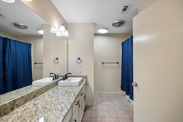 bathroom with a textured ceiling, vanity, and tile patterned flooring