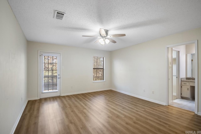 spare room featuring ceiling fan, light hardwood / wood-style floors, and a textured ceiling