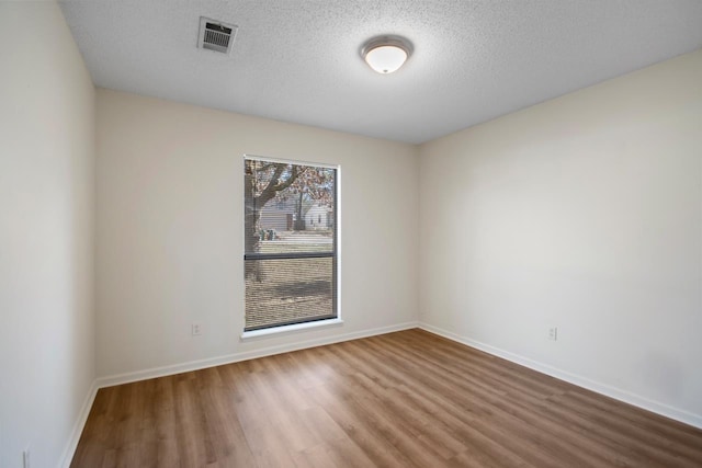 empty room with a textured ceiling and wood-type flooring