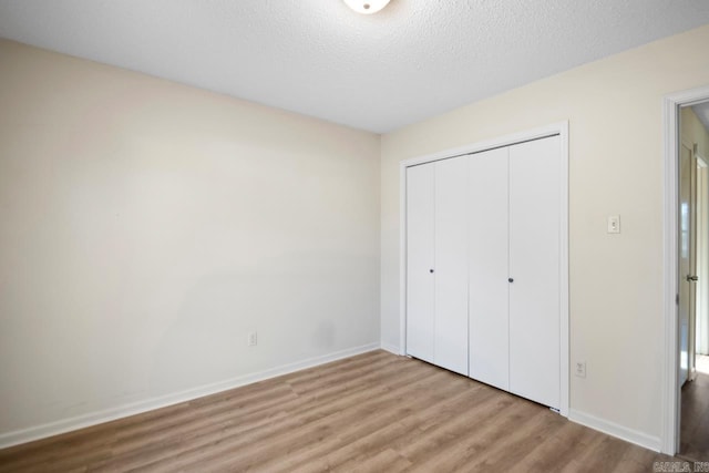 unfurnished bedroom with a textured ceiling, light hardwood / wood-style flooring, and a closet