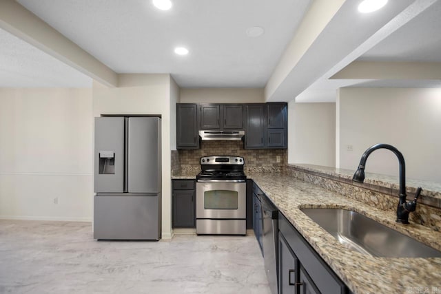 kitchen with light stone countertops, stainless steel appliances, tasteful backsplash, sink, and kitchen peninsula