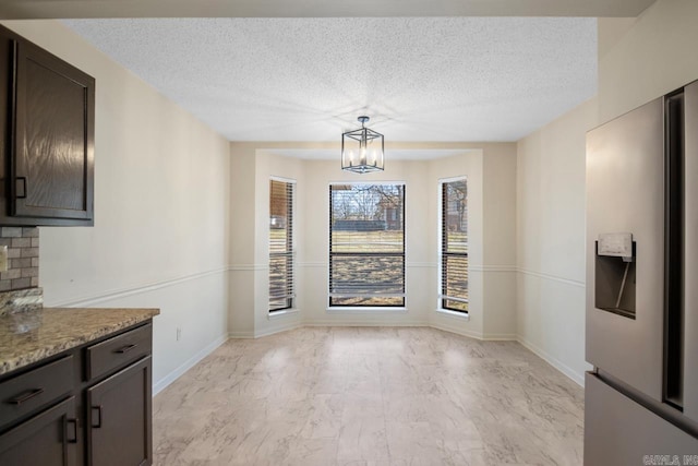 unfurnished dining area with a textured ceiling and a chandelier