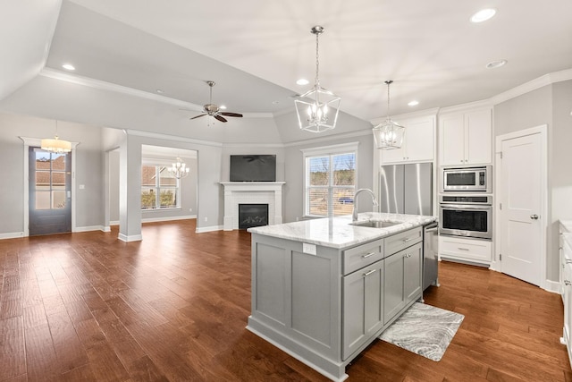 kitchen with sink, decorative light fixtures, appliances with stainless steel finishes, an island with sink, and light stone countertops