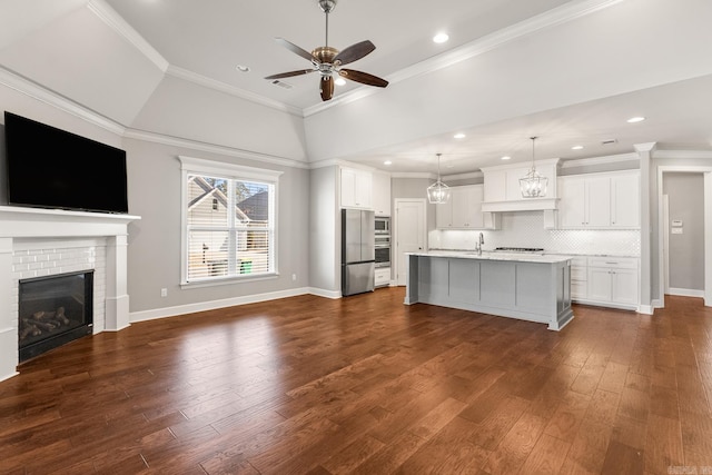 kitchen featuring hanging light fixtures, dark hardwood / wood-style floors, a center island with sink, and white cabinets