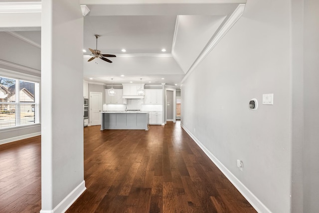 unfurnished living room featuring ceiling fan, ornamental molding, and dark hardwood / wood-style floors