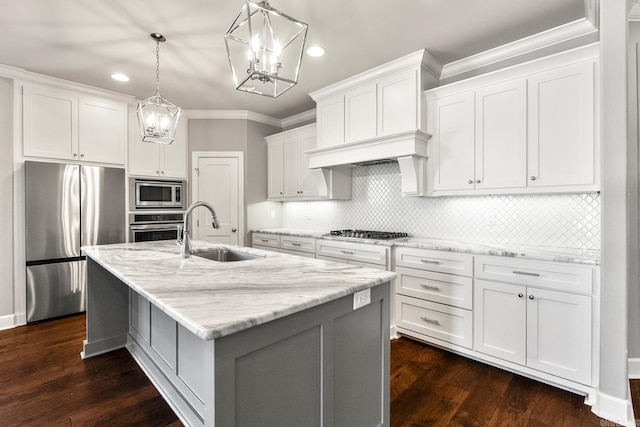 kitchen featuring sink, white cabinets, hanging light fixtures, stainless steel appliances, and a center island with sink