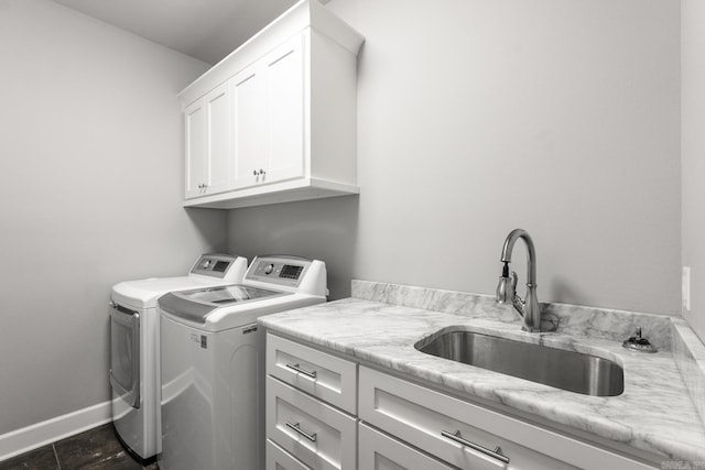 clothes washing area featuring separate washer and dryer, sink, and cabinets