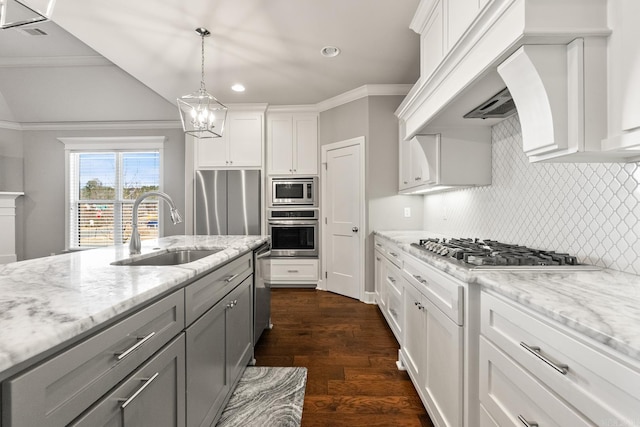 kitchen with sink, white cabinetry, light stone counters, built in appliances, and decorative light fixtures