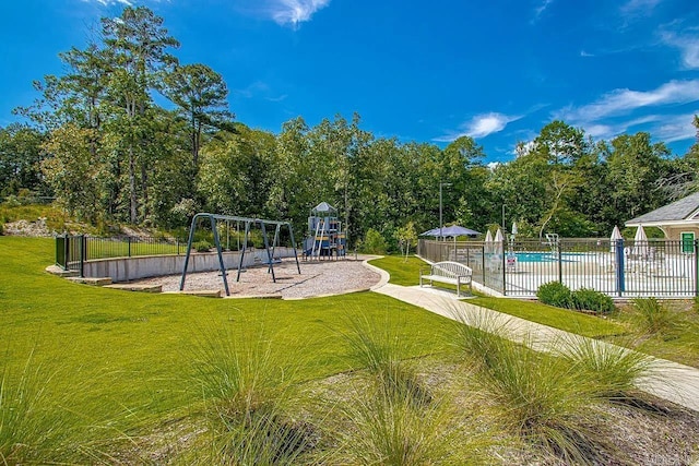 view of property's community with a yard, a swimming pool, and a playground