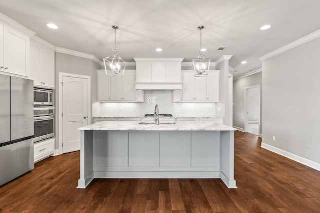 kitchen with stainless steel appliances, a kitchen island with sink, hanging light fixtures, and white cabinets