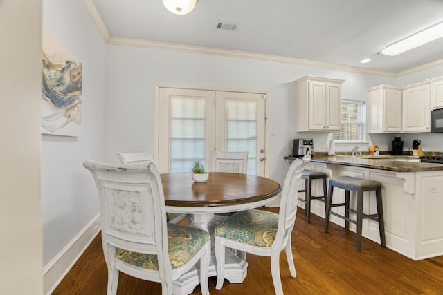 dining space with sink, dark hardwood / wood-style floors, and ornamental molding