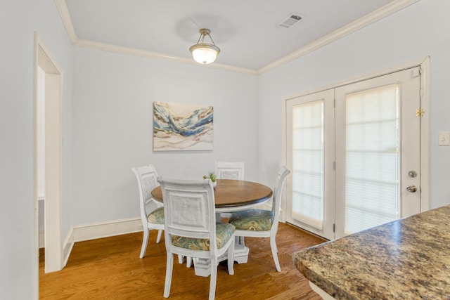 dining room with french doors, crown molding, and wood-type flooring