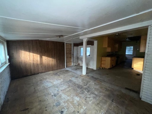 empty room featuring a healthy amount of sunlight, wooden walls, and brick wall