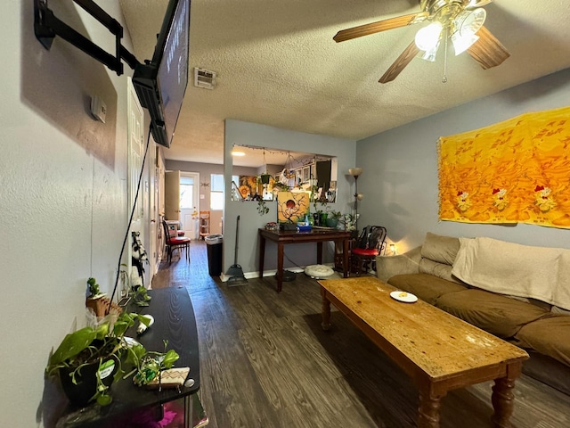 living room featuring ceiling fan, dark wood-type flooring, and a textured ceiling