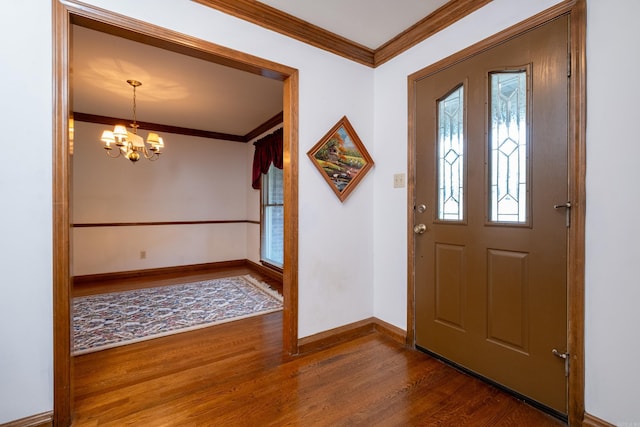 foyer entrance with ornamental molding, dark hardwood / wood-style floors, and an inviting chandelier