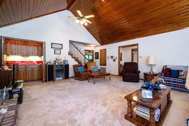 living room featuring wine cooler, ceiling fan, light colored carpet, high vaulted ceiling, and wet bar