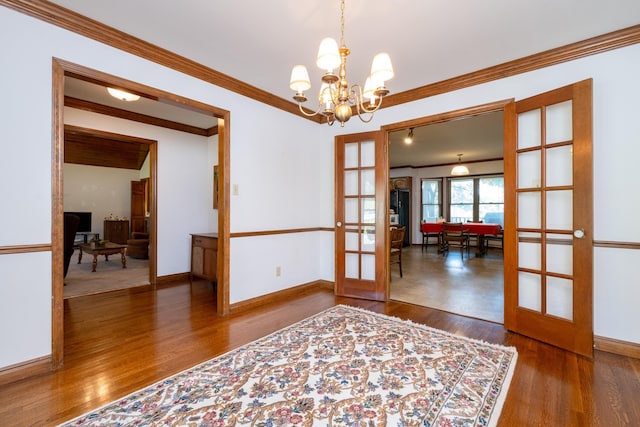 unfurnished room featuring hardwood / wood-style flooring, french doors, crown molding, and an inviting chandelier