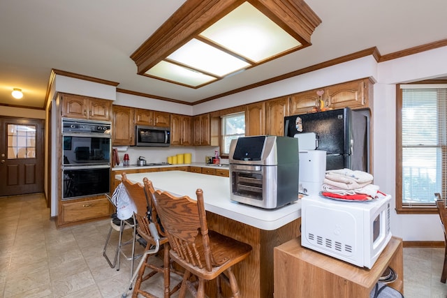 kitchen featuring crown molding, black appliances, and a breakfast bar