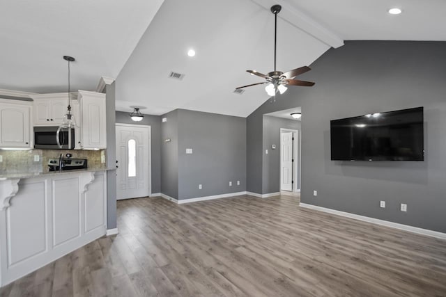 kitchen with backsplash, lofted ceiling with beams, white cabinetry, light stone countertops, and stainless steel appliances