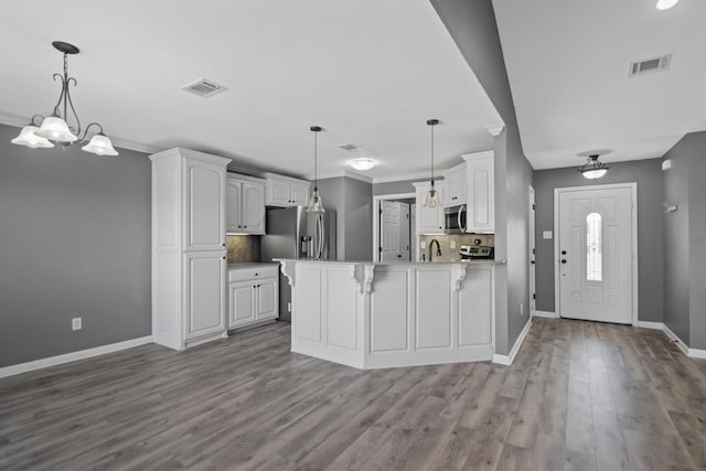 kitchen featuring white cabinetry, hanging light fixtures, sink, light wood-type flooring, and backsplash