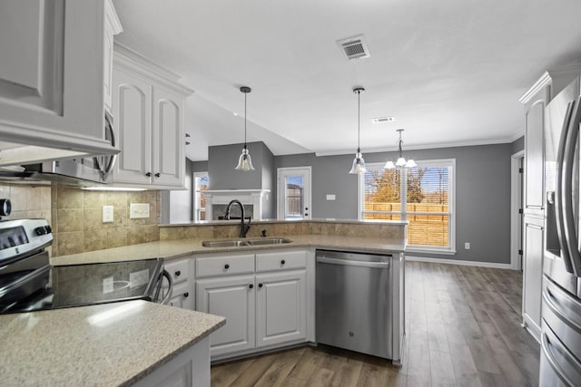 kitchen with kitchen peninsula, sink, backsplash, white cabinets, and stainless steel appliances