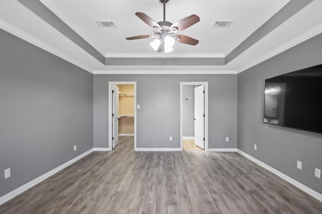 unfurnished bedroom featuring ceiling fan, a closet, a spacious closet, and a raised ceiling