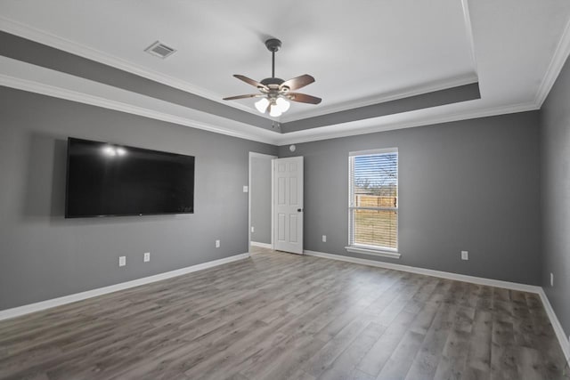 empty room with hardwood / wood-style flooring, a tray ceiling, crown molding, and ceiling fan