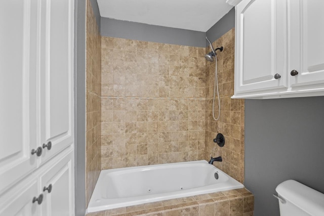 bathroom featuring tiled shower / bath combo and toilet