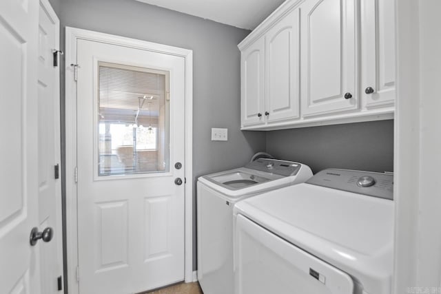 clothes washing area with cabinets and washing machine and clothes dryer