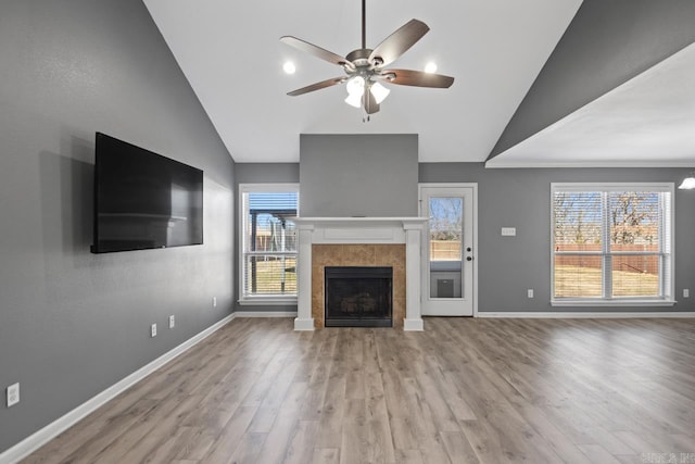 unfurnished living room featuring plenty of natural light, a tile fireplace, and lofted ceiling