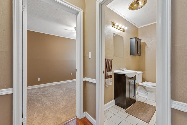 bathroom with tile patterned flooring, ornamental molding, toilet, a textured ceiling, and vanity