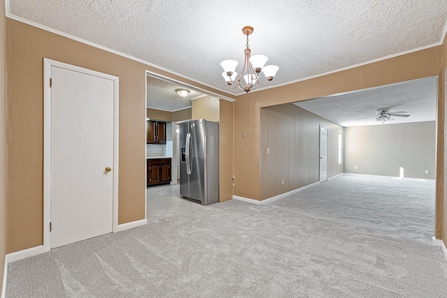 spare room featuring ceiling fan with notable chandelier, a textured ceiling, ornamental molding, and light carpet