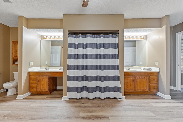 bathroom with vanity, toilet, a textured ceiling, and wood-type flooring