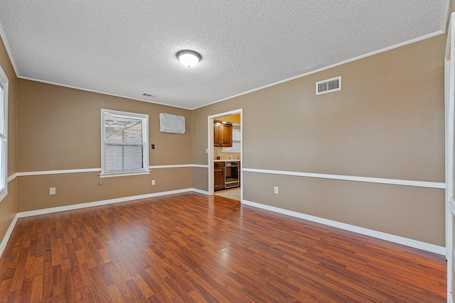 empty room with hardwood / wood-style flooring, ornamental molding, and a textured ceiling