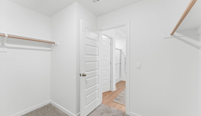 walk in closet featuring light carpet