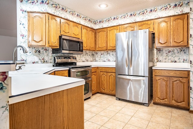 kitchen featuring sink, a textured ceiling, light tile patterned floors, and stainless steel appliances