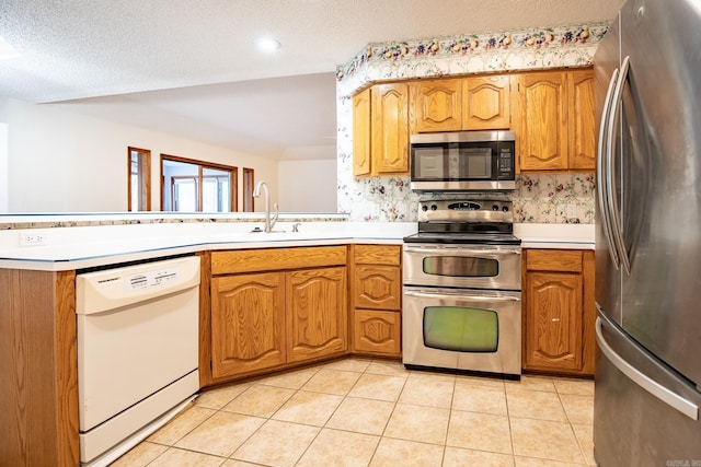 kitchen featuring a textured ceiling, sink, kitchen peninsula, stainless steel appliances, and light tile patterned flooring