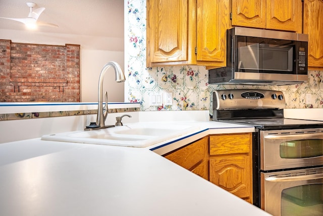 kitchen with decorative backsplash, sink, stainless steel appliances, and ceiling fan