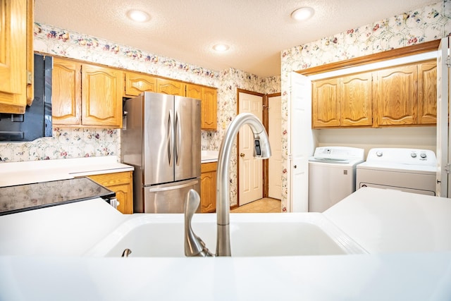 kitchen featuring a textured ceiling, stainless steel fridge, and washing machine and clothes dryer