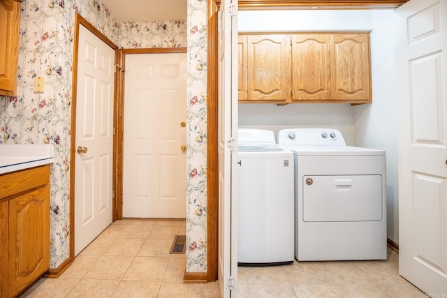 laundry room with light tile patterned floors, cabinets, and washer and clothes dryer