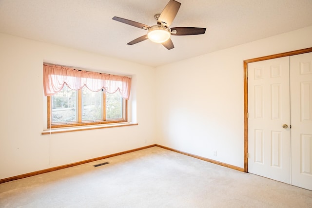 unfurnished bedroom with light carpet, a closet, and ceiling fan